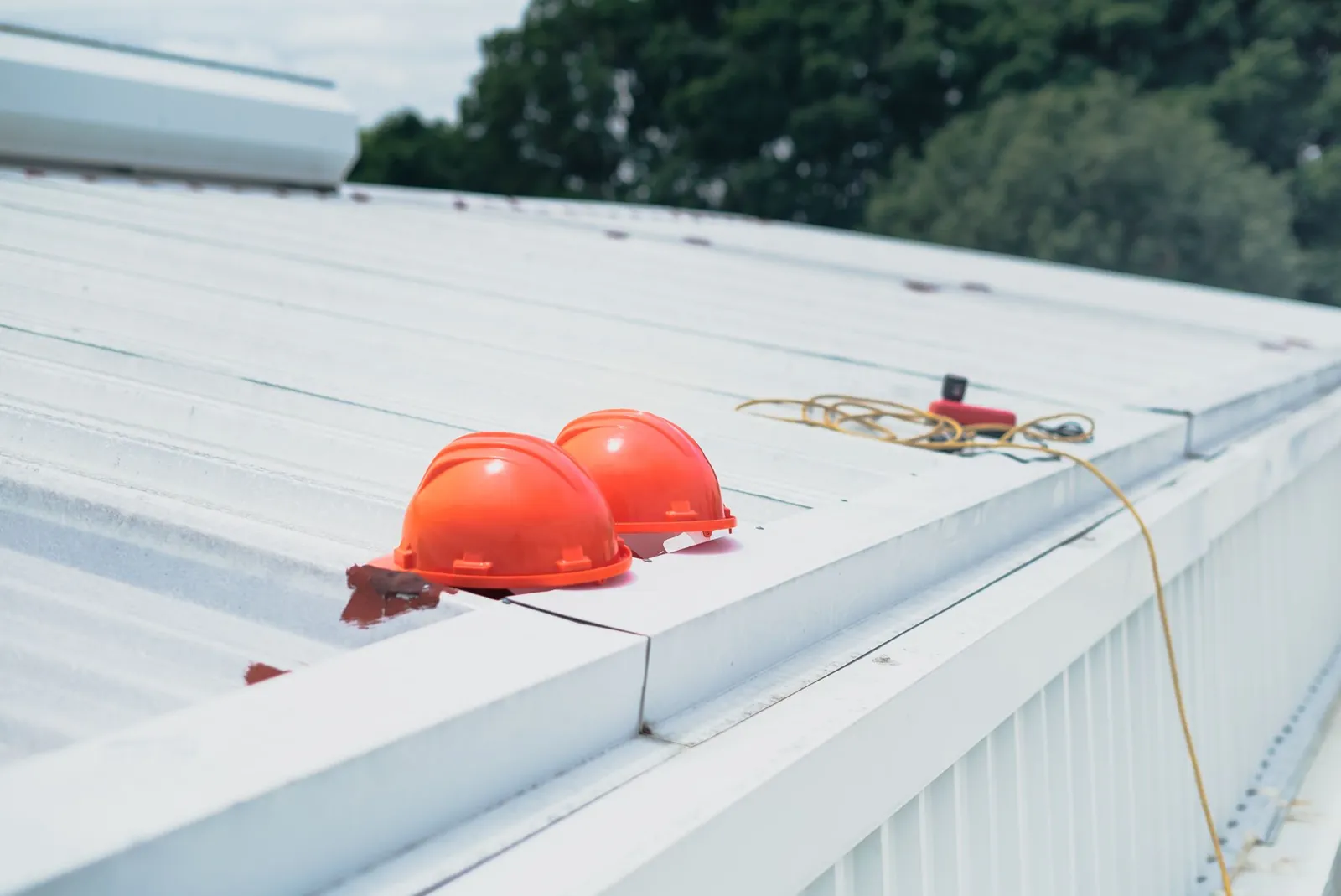 Hard hats resting on newly installed metal roof panels during construction.