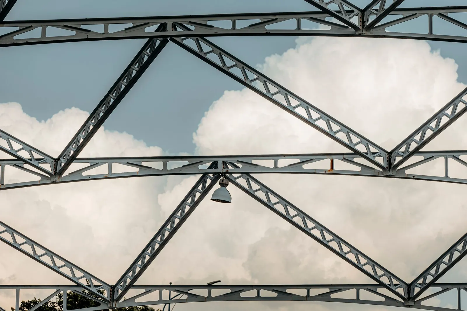Steel roof trusses seen from below with open sky, before the roof panels are installed.