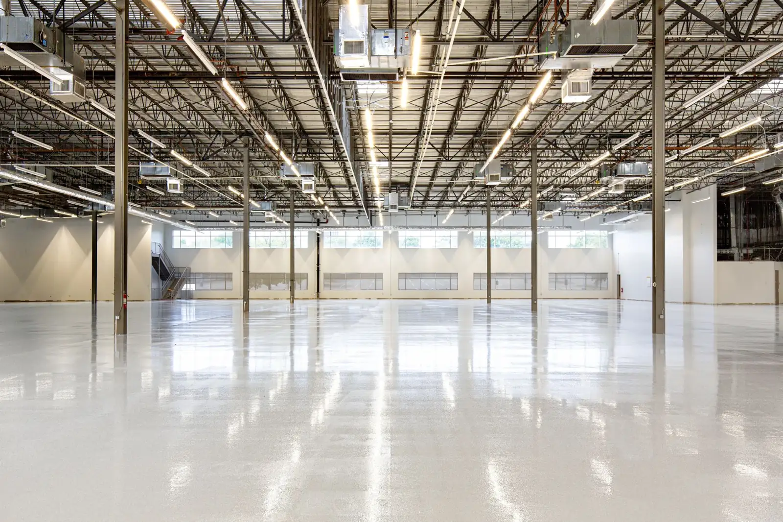 Large empty warehouse with steel columns, open-web joists and roof deck after construction.